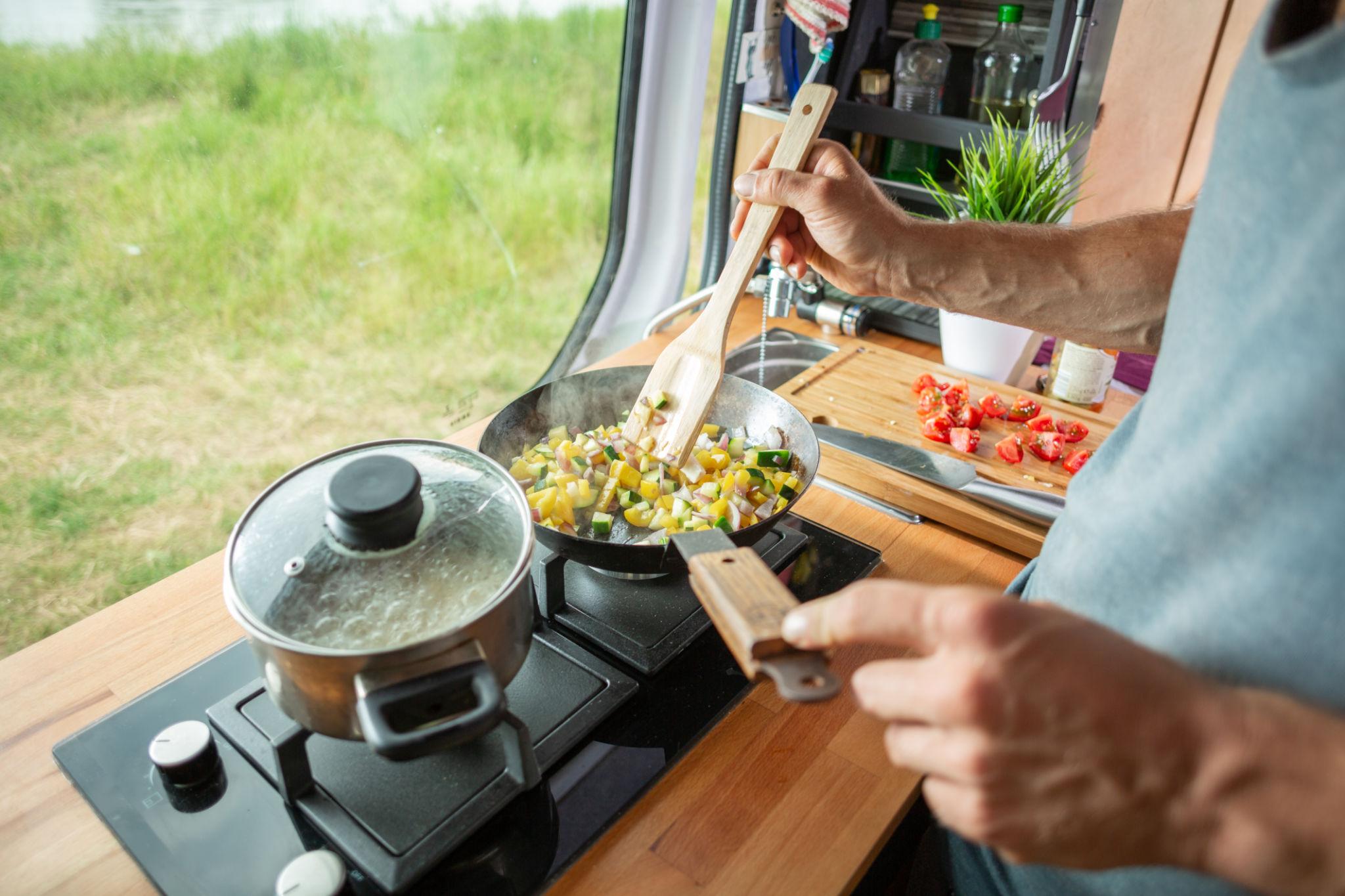 Person cooking inside RV showing food costs for full time RV living