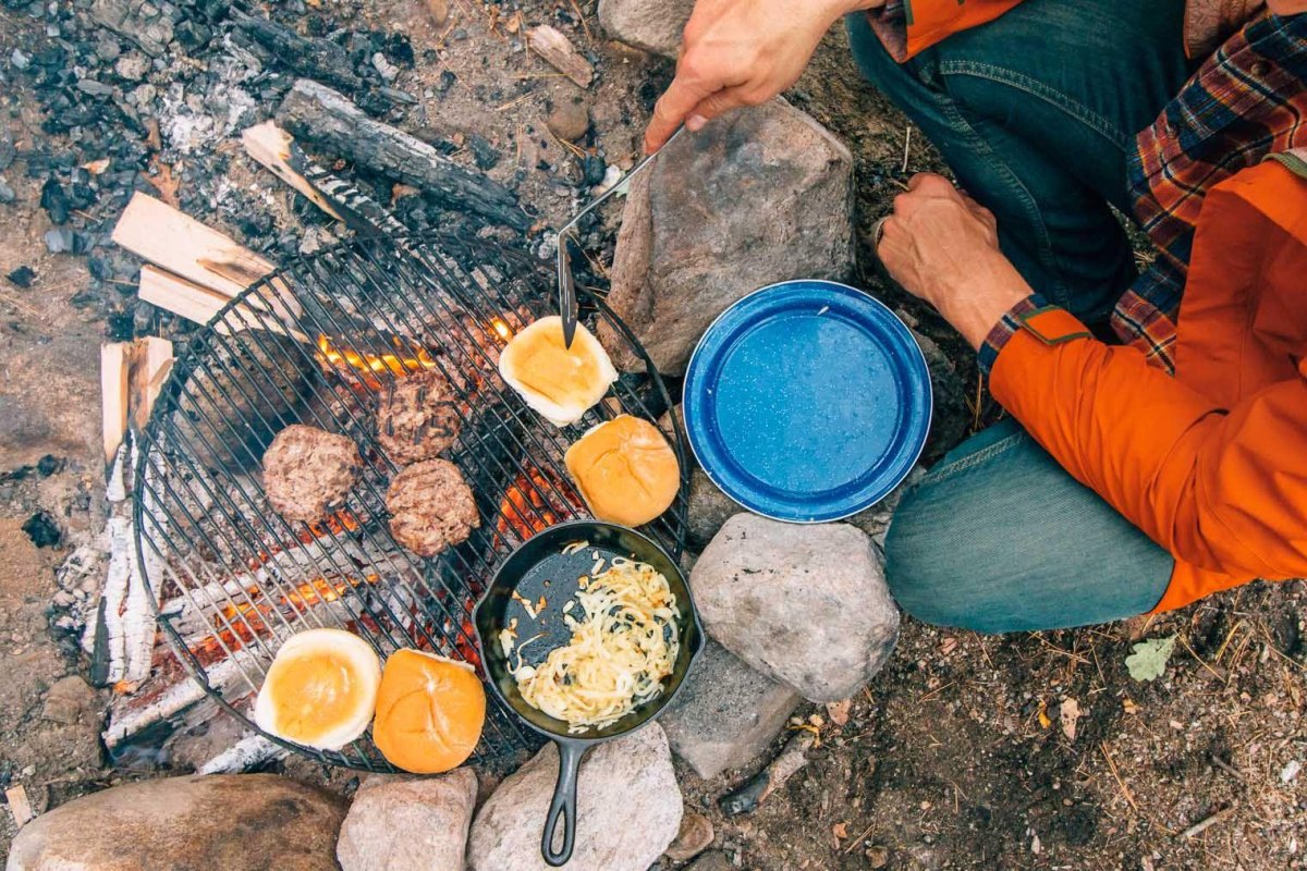 Grilled burgers beside campfire
