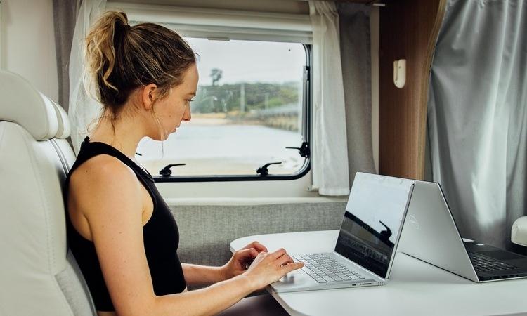 Traveler using laptop inside RV showing internet costs for full time RV living